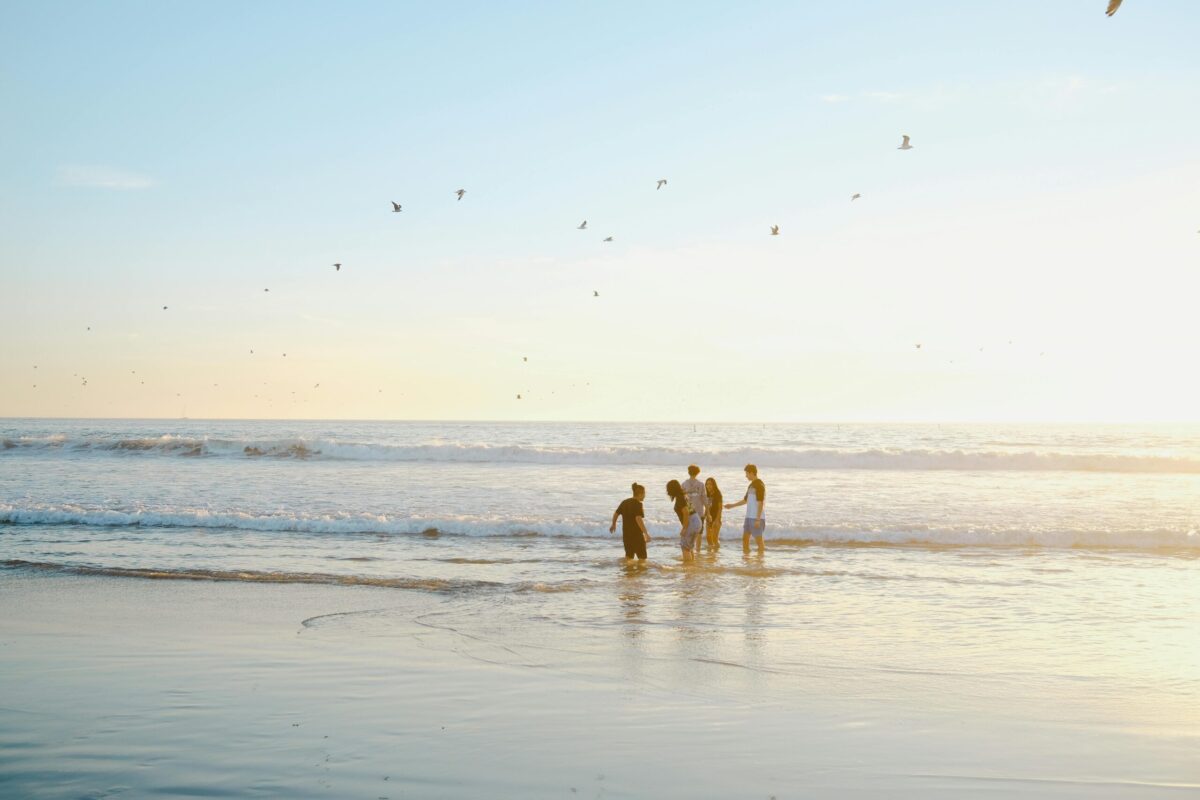 Photo d'un groupe au loin sur la plage, les pieds dans l'eau